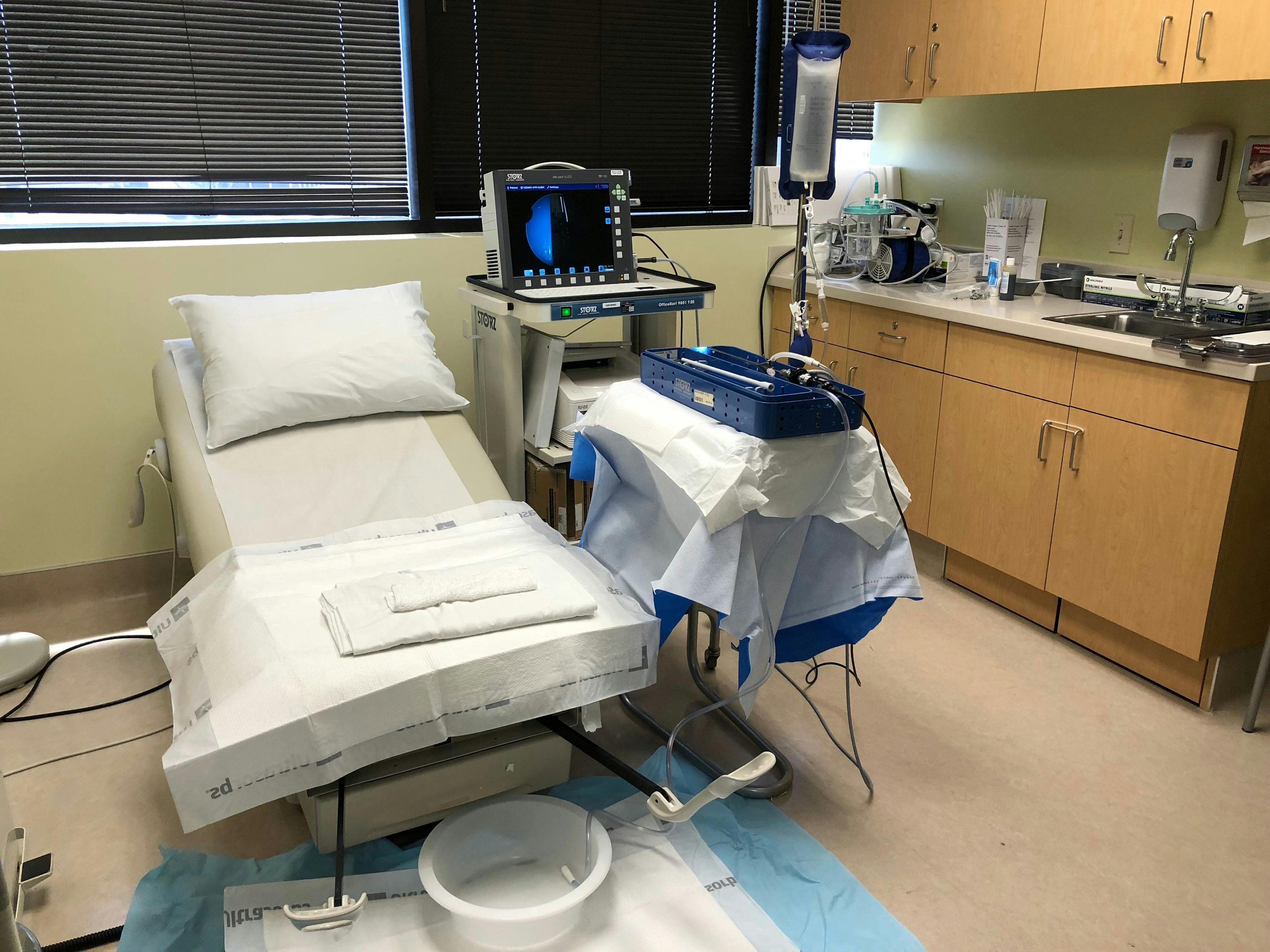 Figure 1. This exam room setup shows all the necessary components for office hysteroscopy, including a bed with stirrups, video system with camera and light cord, sterilized hysteroscope on a mayo stand with infl ow coming from a pressure bag on an IV pole and outflow to gravity in a basin, and a tabletop suction for tissue extraction devices.