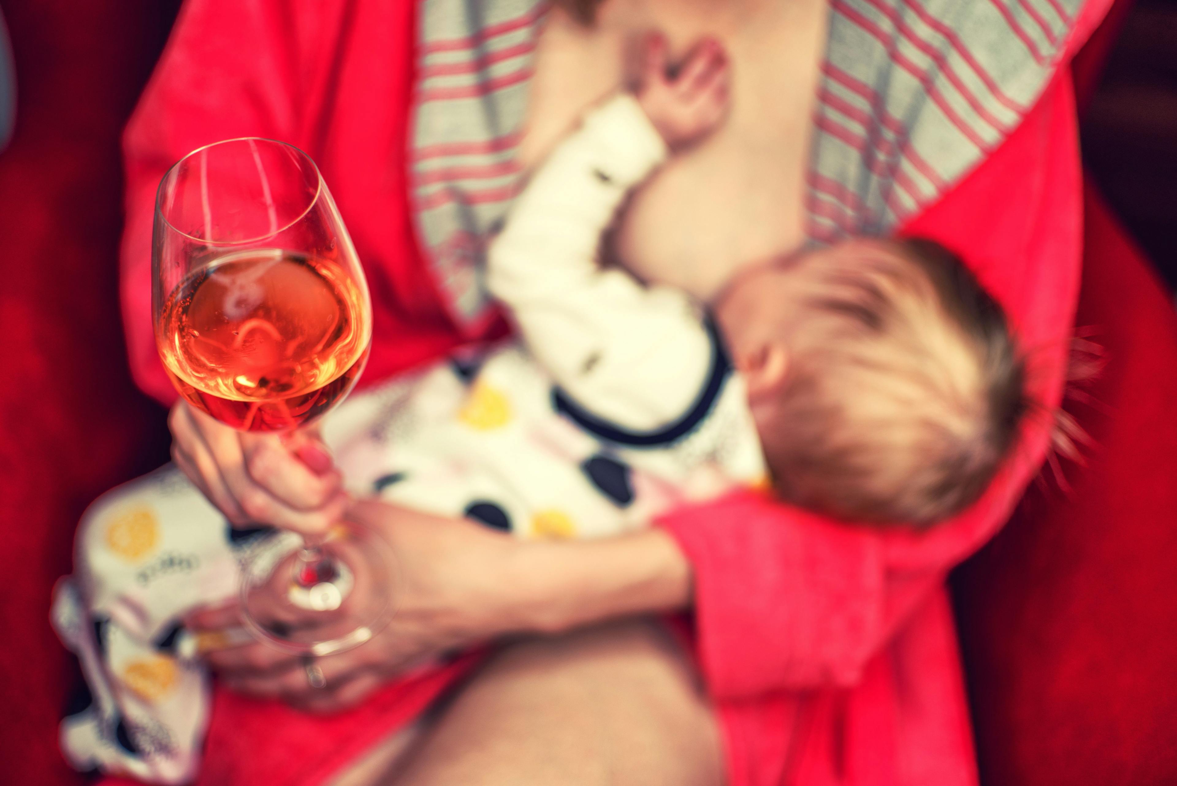 Woman drinking alcohol wine while breastfeeding child
